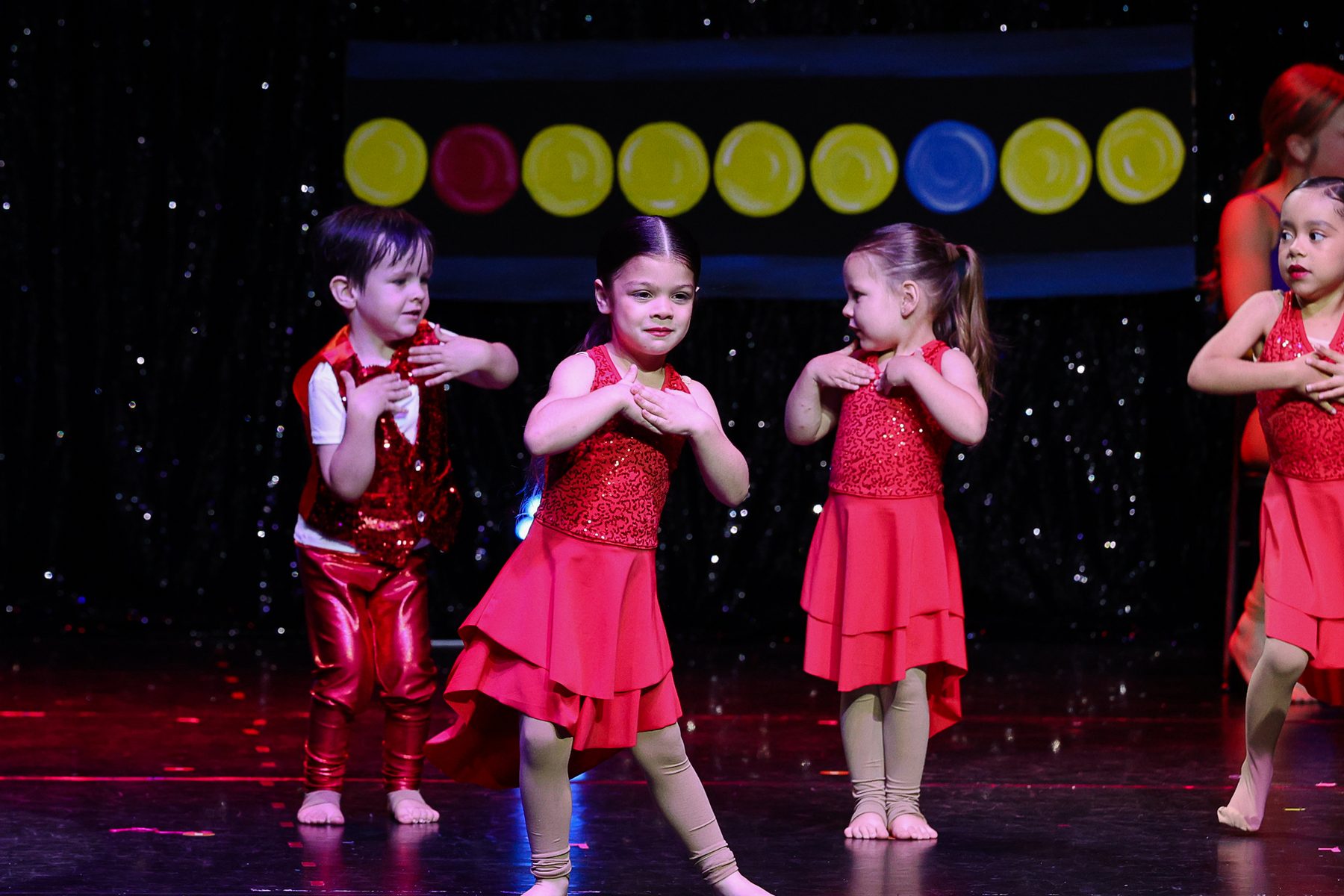 Young dancers in red sequin costumes on stage at an Ignite Your Flare recital