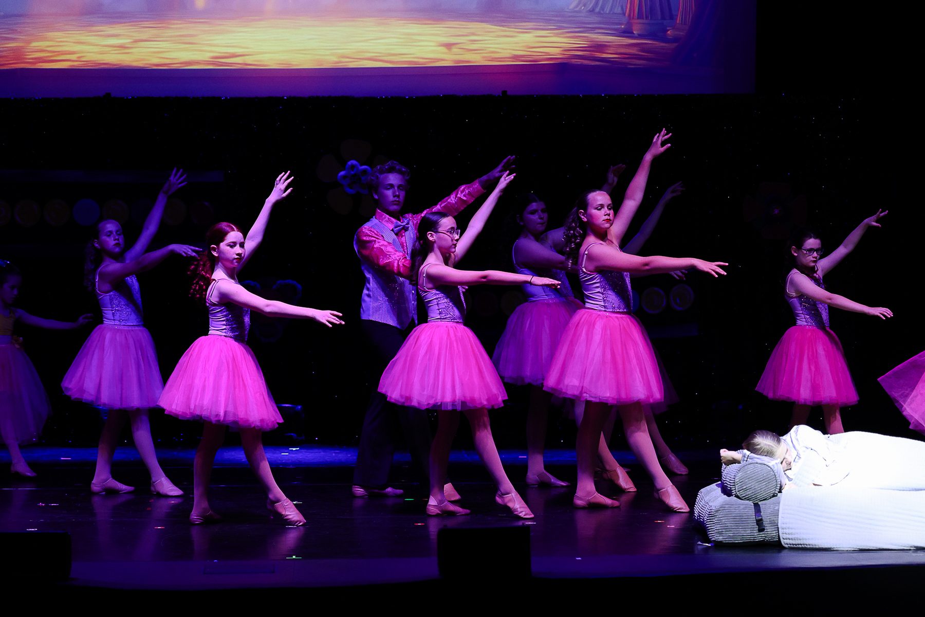 Ballet dancers in pink tutus reaching across the stage at an Ignite Your Flare recital