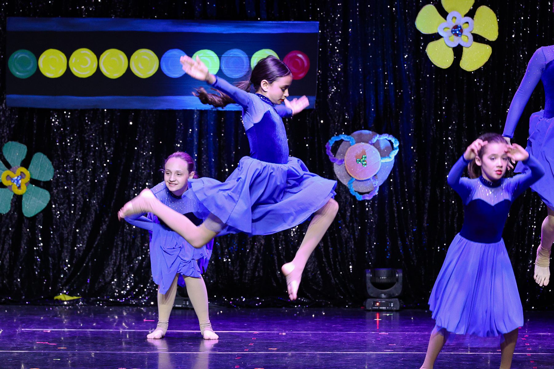 A lyrical dancer leaping in a blue dress at an Ignite Your Flare recital